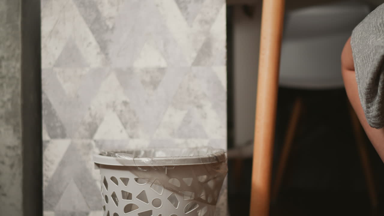 Person discarding food waste into a trash can