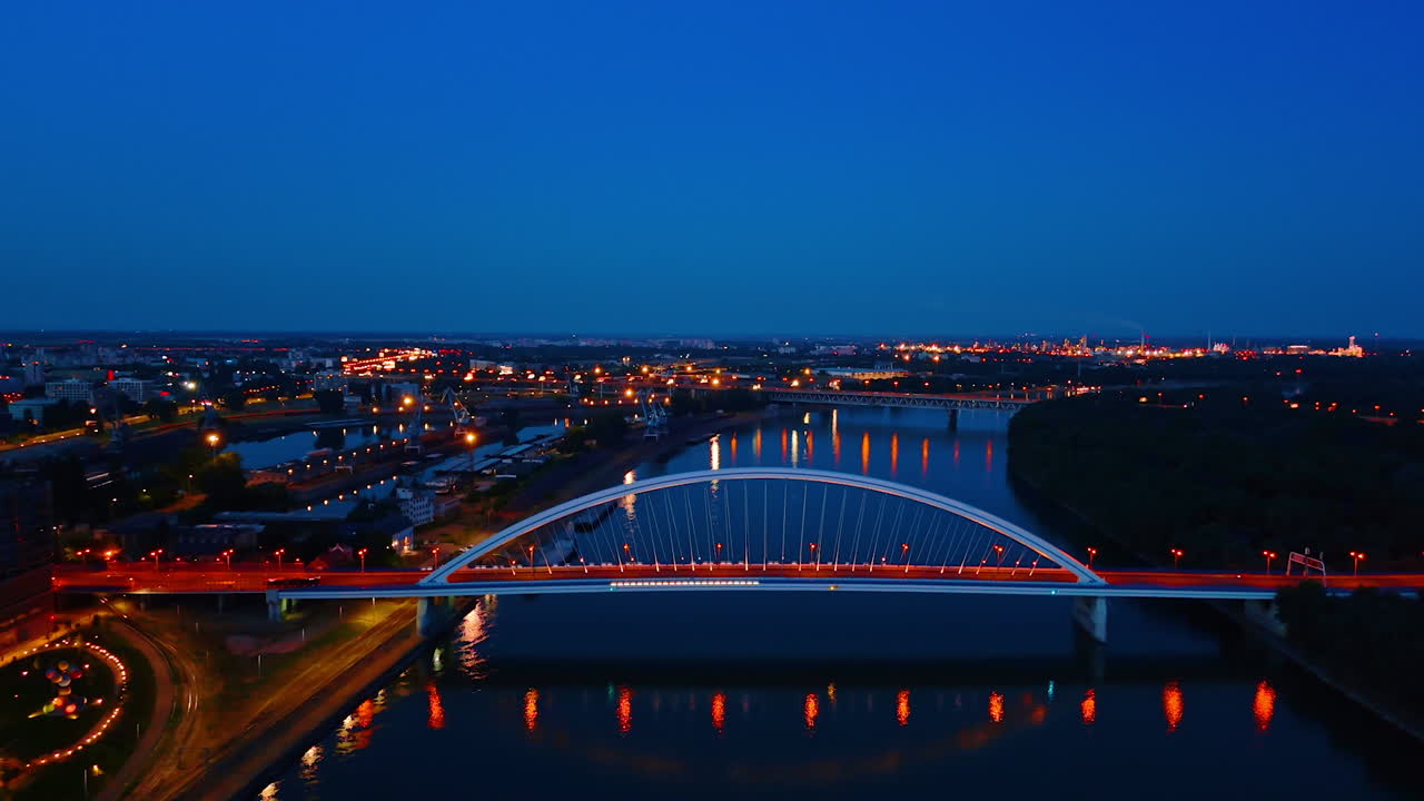 Dark waterscape of the Danube reflecting lights at dusk time. Drone footage over the river flowing in Bratislava, Slovakia
