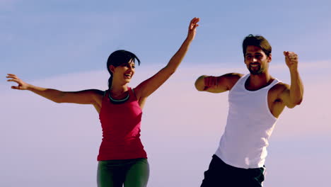 man and woman jumping together on the beach