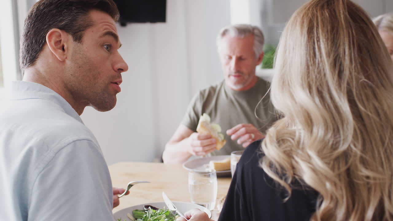 семья с пожилыми родителями и взрослым потомством ест еду за столом дома вместе