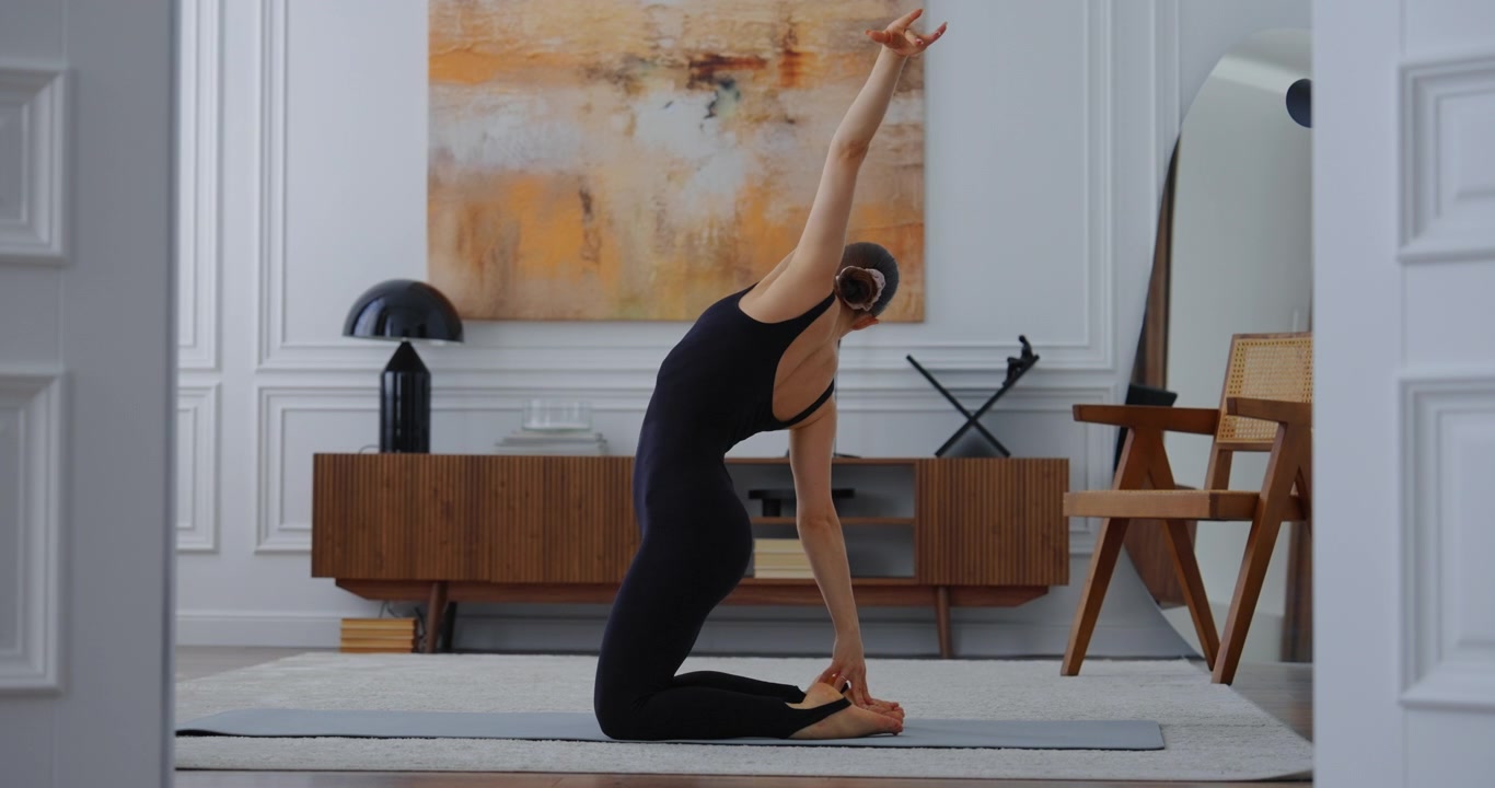 Jovem mulher praticando alongamento de yoga com flexão para trás em casa.