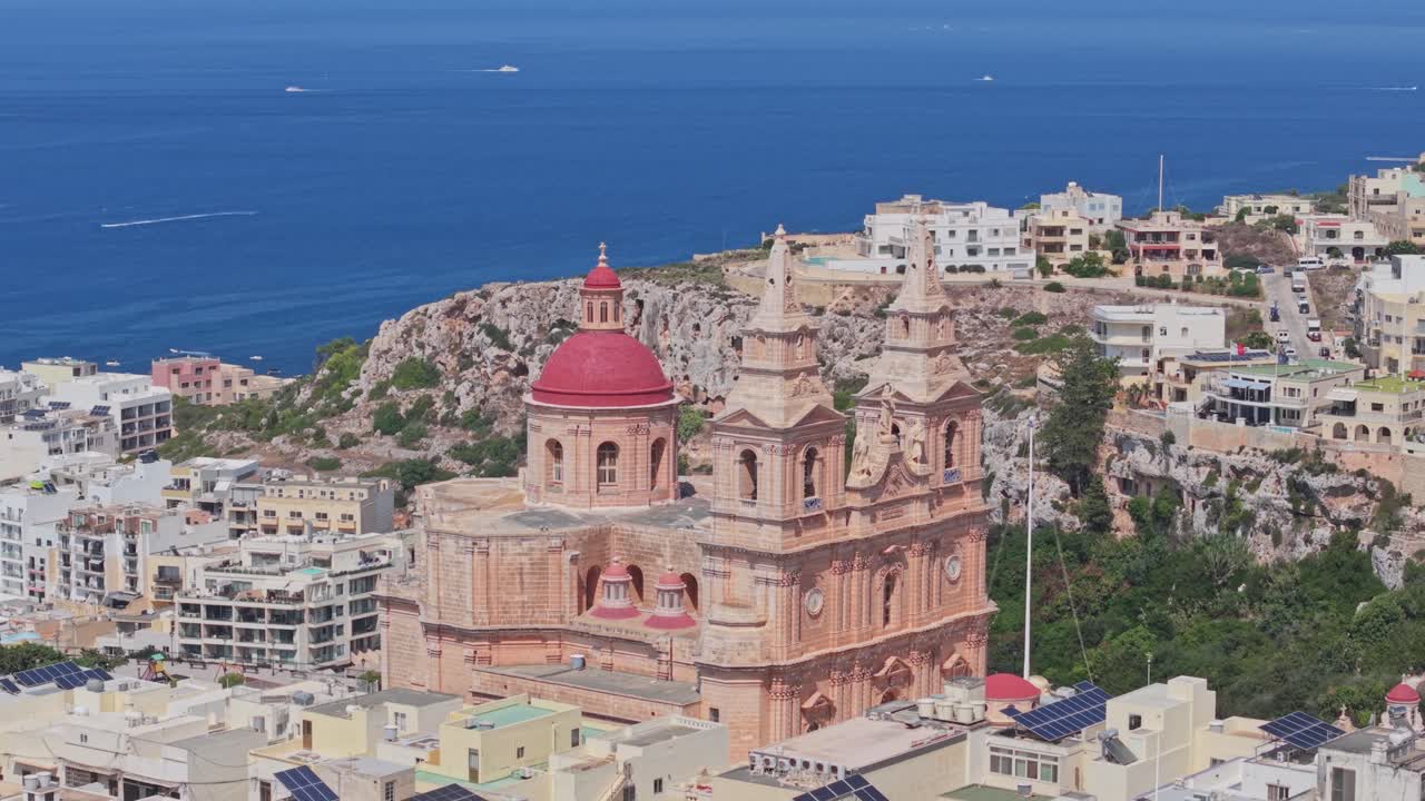 Aerial view of the Mellieha Parish Church with its iconic red dome and twin bell towers, overlooking the Mediterranean Sea in Malta