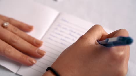 woman writing in a journal on a white table cloth