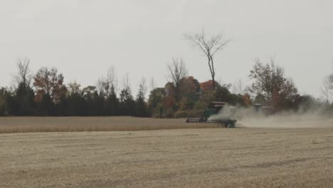 agricultural tractor harvesting on the field with dust in autumn