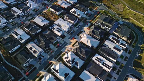 overhead drone view of a new canberra suburb with fresh houses and vibrant autumn trees adding color to the streetscape.