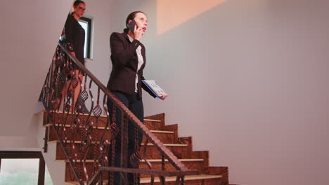 Furious-office-executive-talking-phone-walking-on-stairs