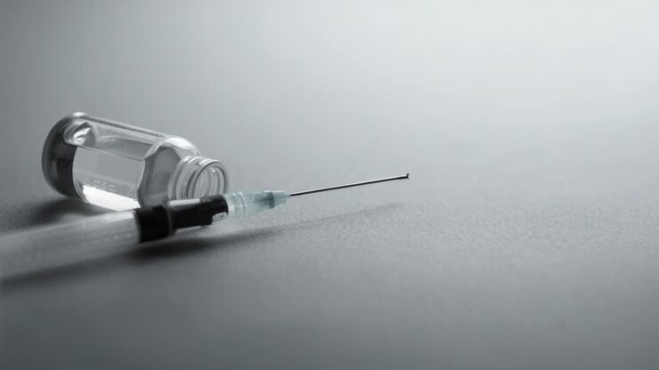 Starting playback showing hypodermic syringe and glass vial lying on matte grey surface, copy space