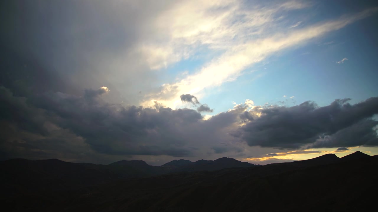 Dramatic Sunset Clouds Over Silhouetted Mountain Range