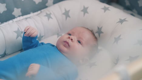 cute newborn kid and mommy shaking rattle over crib closeup