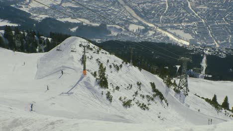 Vview-of-Innsbruck-from-Nordkette-ski-resort,-with-chairlift-and-skiers