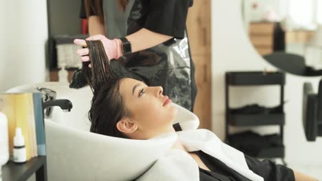 Portrait-of-pretty-Caucasian-young-woman-combing-hair-while-coloring-in-beauty-and-health-salon