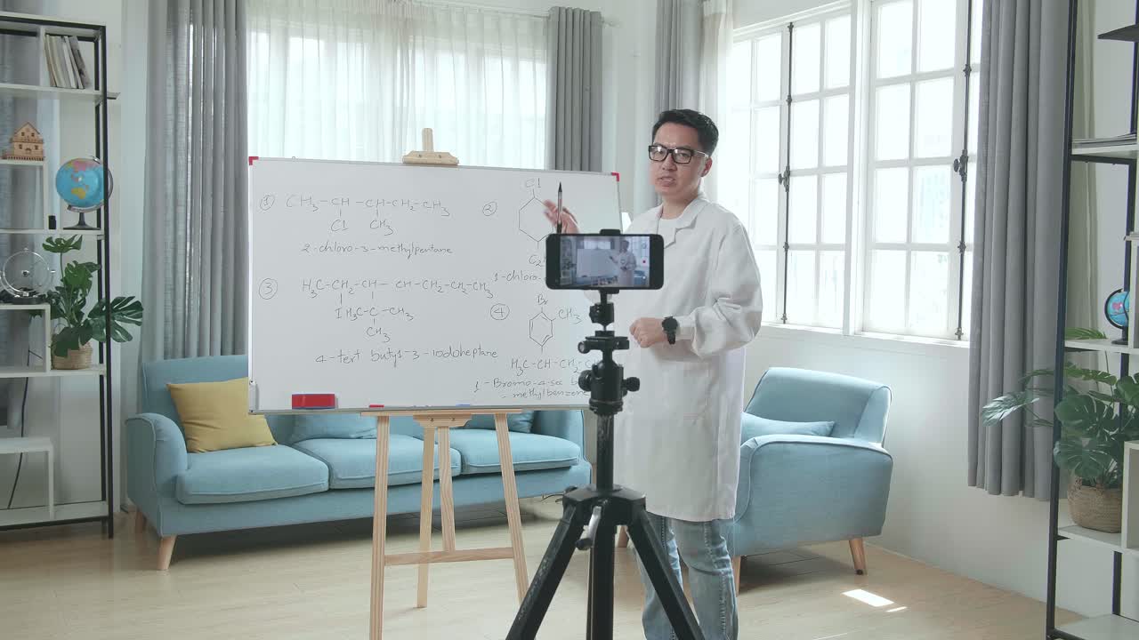 Guru Pria Asia Berkacamata Merekam Video dengan Kamera Ponsel Sambil Mengajar Kimia di Rumah