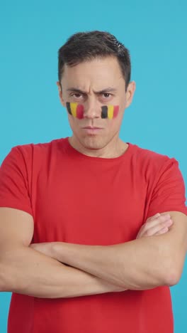 dignified and serious man with belgian flag painted on face