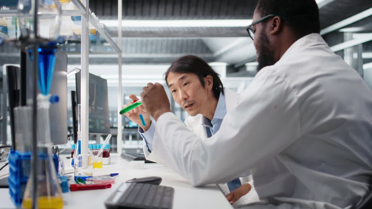 Vertical video Diverse team of lab chemists inspecting chemical solutions in glass flasks