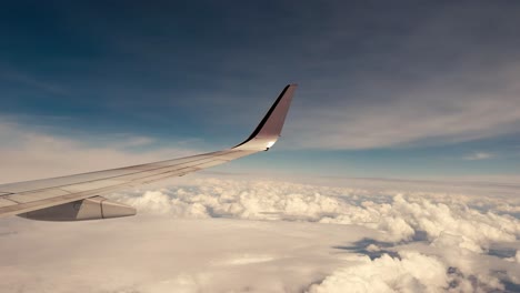 looking out the window of an airplane at an airplane wing with clear blue skies and clouds below