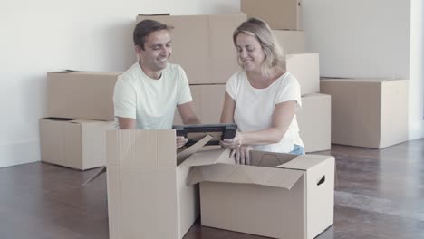 cheerful family couple unpacking things in new apartment