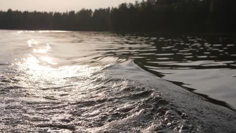 Große-Welle-Auf-Einem-See,-Während-In-Einem-Boot-Mit-Sonne-Im-Hintergrund-Scheint-Verschwommenen-Wald-Stimmungsvolle-Abendatmosphäre