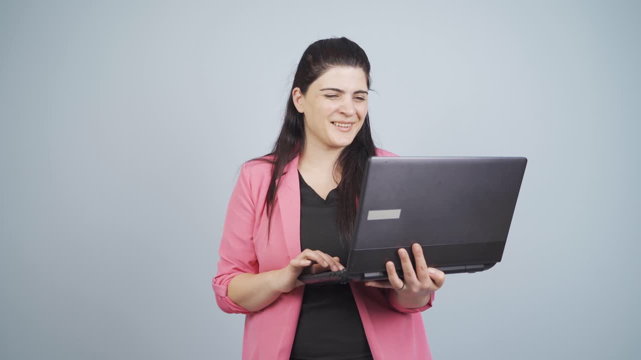 una mujer de negocios satisfecha mira la computadora portátil y aprueba.