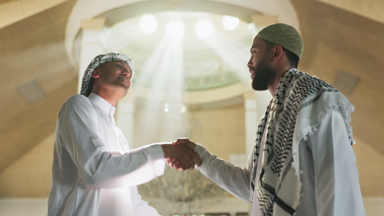 Two Muslim men in traditional clothing meeting indoors