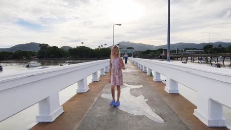 young girl walking on a pier by the ocean