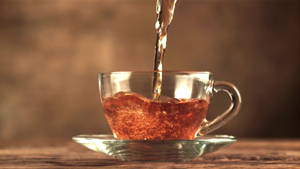 Tè caldo che si versa in una tazza di vetro al rallentatore