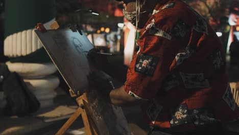 amidst an india celebration, an artist skillfully creates a portrait of a man using black ink on canvas during the night.
