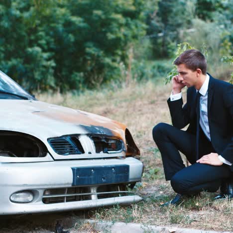 un hombre con traje inspecciona un auto después de un accidente