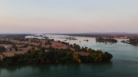 drone view at sunset over the mekong river in southern laos, showing the braided channels and islets near don det in the si phan don region, with dry-season farmland and tree cover along the banks