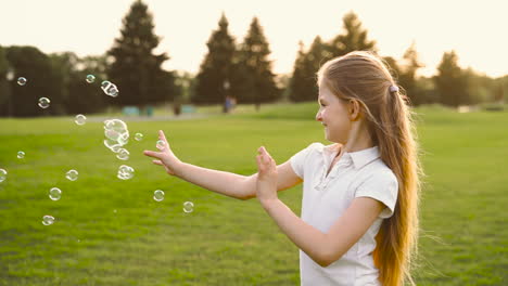 Glückliches-Kleines-Mädchen,-Das-Im-Park-Seifenblasen-Fängt