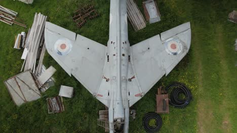 rising aerial view above wings of distressed hawker hunter fighter aircraft on british renovation farmland yard