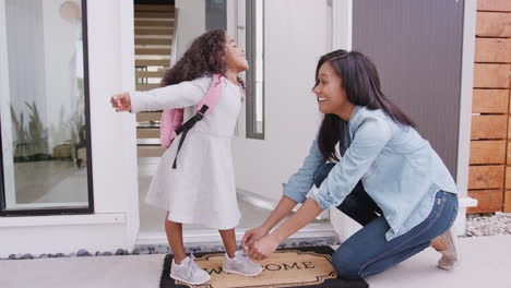 mother tying daughters shoelaces as she leaves for school