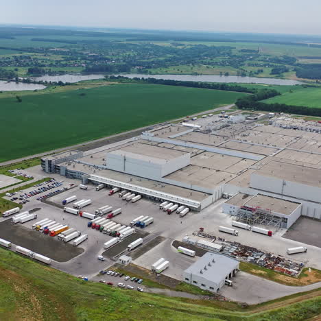aerial view of a modern industrial territory in the countryside. huge manufacturing structure with several car parking outdoors.