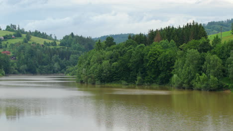 Agua-En-Movimiento-En-La-Superficie-Del-Embalse-Durante-El-Día-Con-La-Naturaleza-Circundante-Llena-De-Bosques-Y-árboles-En-Los-Bordes-Del-Embalse-Bystricka