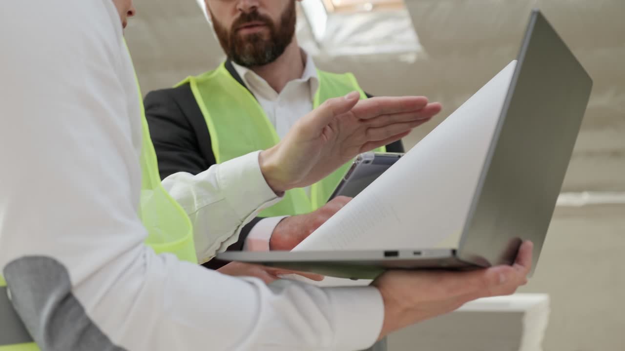 equipo de ingeniería civil junto con el arquitecto y el capataz viendo el plano y la aplicación de portátil planeando la construcción del edificio en el sitio de construcción. ingenieros con cascos de seguridad.