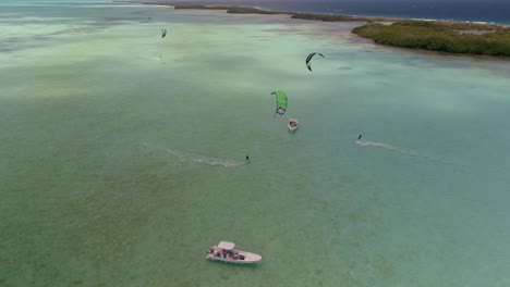 Drone-shot-turn-around-boat-stand-waiting-friends-practing-kiteboard,-Salinas-los-Roques