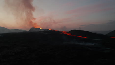 Forwards-fly-over-volcanic-landscape-at-dawn.-Rising-smoke-from-active-volcano-and-flowing-lava-streams-on-ground.-Fagradalsfjall-volcano.-Iceland,-2021