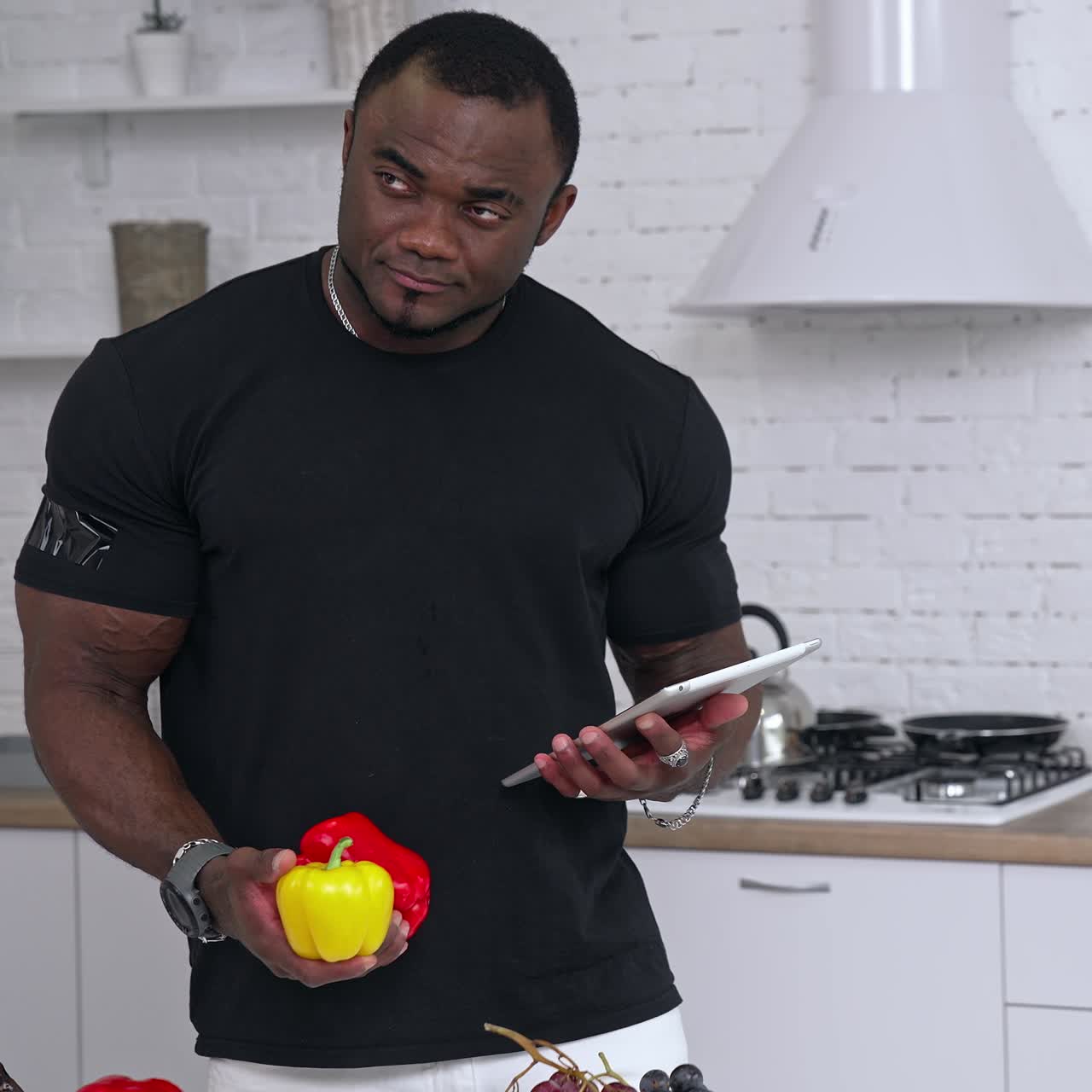 Multiracial man in kitchen ready to prepare meal with vegetables and fruits. Guy is holding pepper. Kitchen background. Healthy food. Vegans and vegetarians