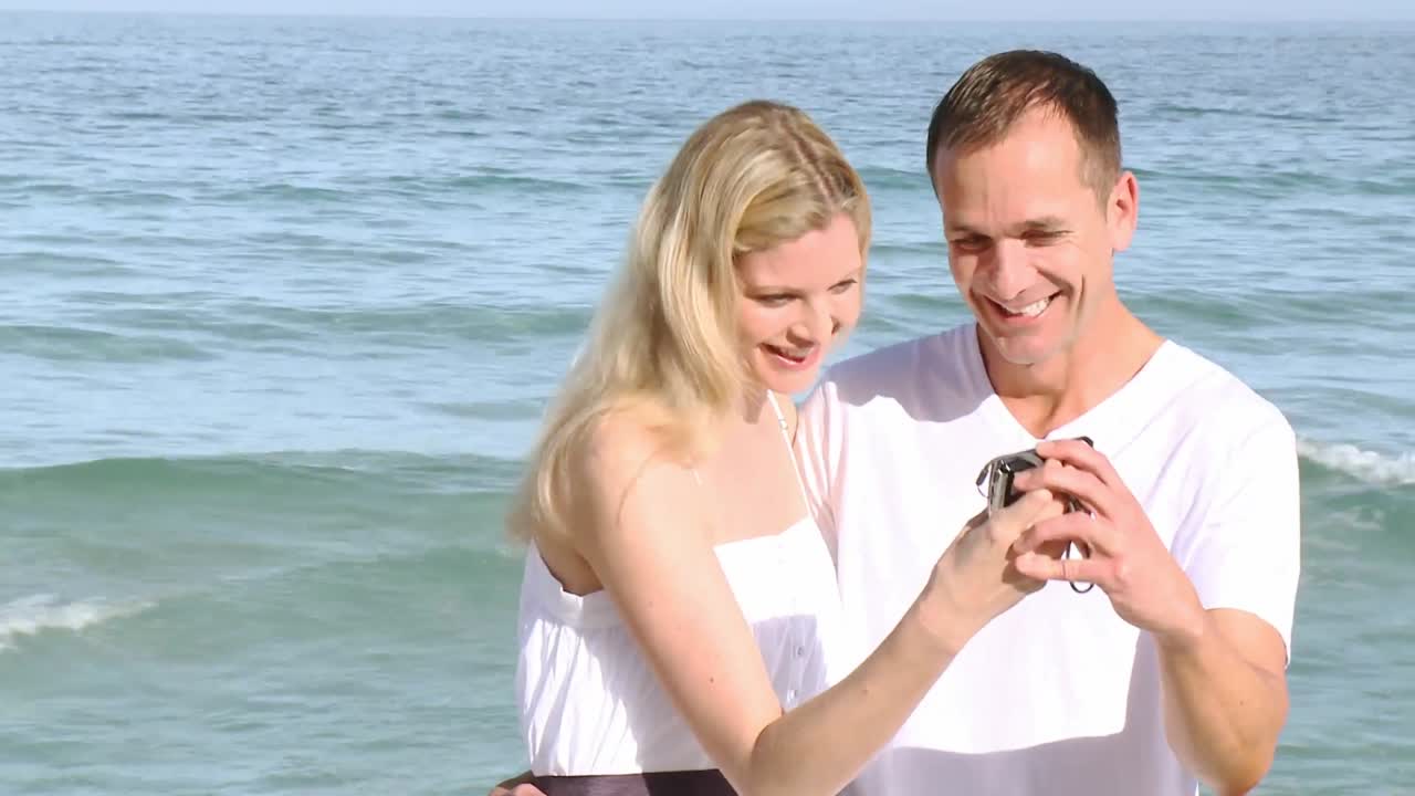 Close up of couple on the beach taking photos of themselves
