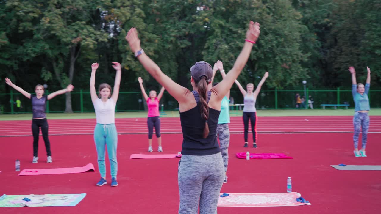 Young athletes doing exercise outdoors. Group of young people performing outdoors