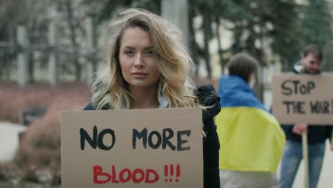 woman in front of group of young caucasian people manifesting against war in ukraine.