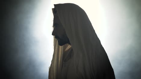 jesus christ resurrected on easter sunday inside empty tomb in bright, shining light, wearing white hood and robe. cinematic christian resurrection visual.