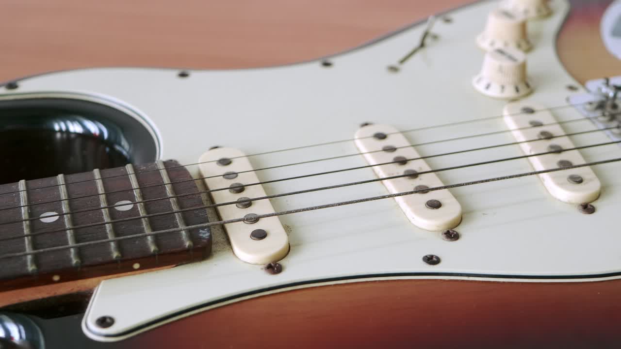 deslice el movimiento de la vieja guitarra eléctrica con un patrón fino de cuerdas de guitarra colocadas sobre una mesa de madera