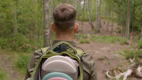 disc golfer walks on a disc golf course in the forest - medium close up shot