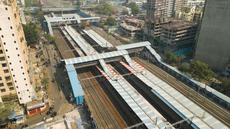 Aerial-dolly-tilt-up-to-establish-Mumbai-Train-station-bustling-with-cars-in-transit,-India