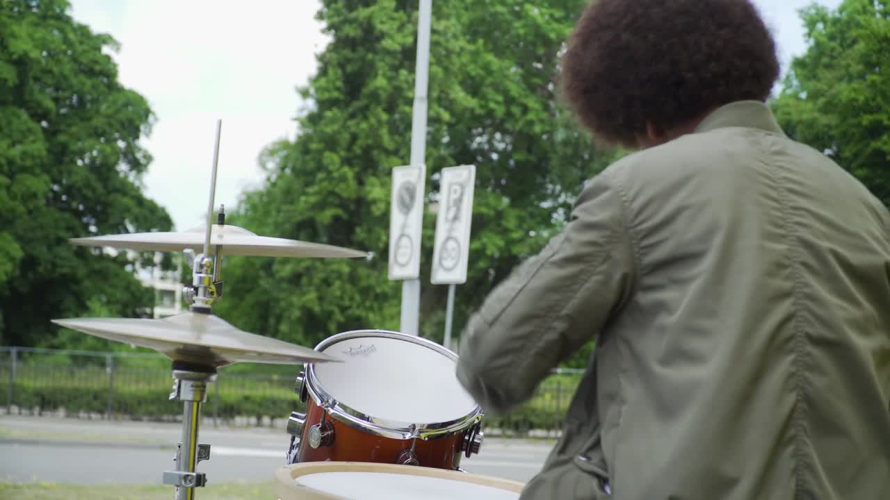 joven baterista afro afuera. posiblemente un artista callejero