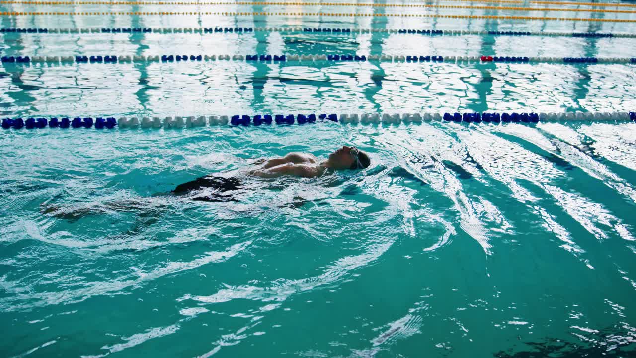 En svømmer, der flyder elegant i en krystalklar pool, indfanger roen og vandbevægelsernes flydende natur i et vandmiljø