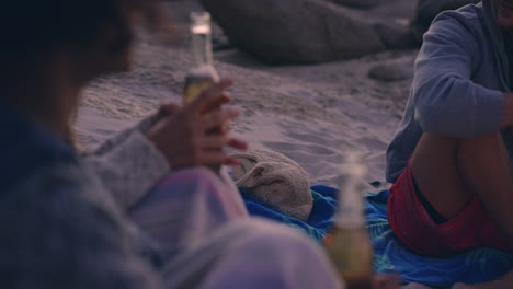 Beach-bonfire-with-group-of-friends,-drinking-beer-and-playing-guitar