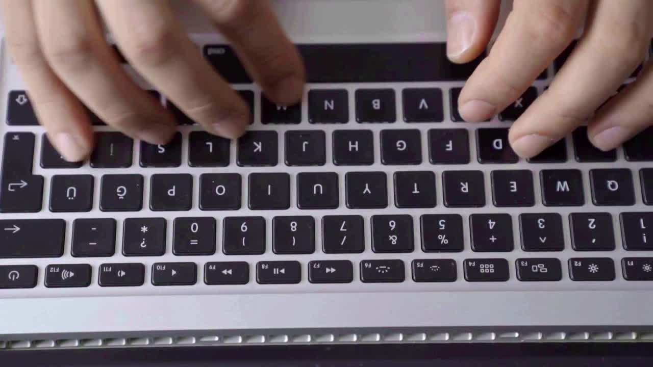 Close-up fingers typing on laptop keys, crisp keystroke rhythm