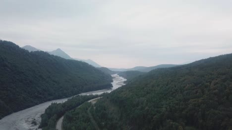 Aerial-view,-drone-flight-along-the-Glenn-Highway-and-the-Matanuska-River-in-the-Chugach-Mountain-Range-of-central-Alaska-on-a-cloudy-summer-day