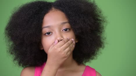 young cute african girl with afro hair covering mouth as three wise monkeys concept